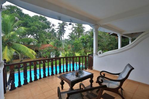 a balcony with a table and chairs and a pool at Sandali Walauwa in Bentota
