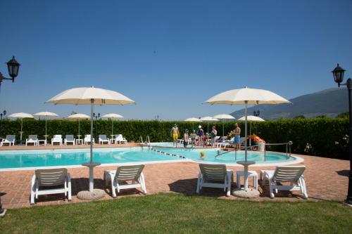 - une piscine avec des chaises longues et des parasols dans l'établissement Terre Del Cantico Country House, à Spello
