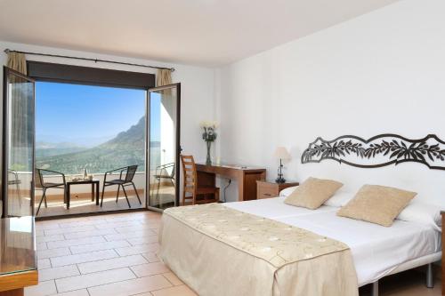 Un dormitorio con una cama y un balcón con una mesa. en Los Castillarejos Apartamentos Rurales, en Luque