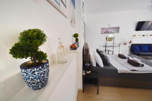 a plant in a blue and white vase next to a bed at PMP Adamia Apartments in Peyia