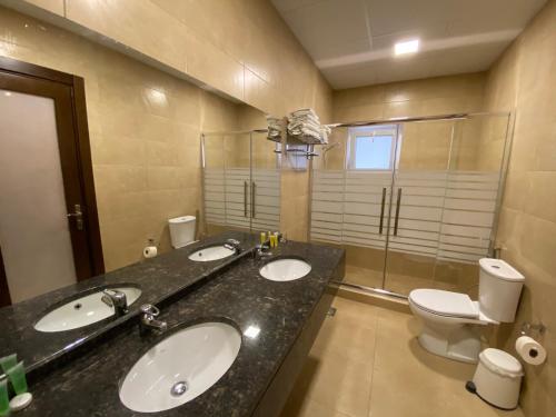 a bathroom with two sinks and a toilet at Mosaic City Hotel in Madaba