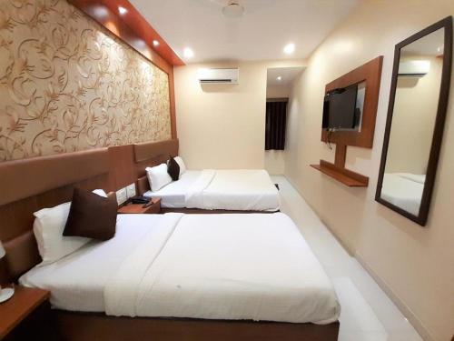a hotel room with two beds and a television at Hotel Durga Elite Mumbai in Mumbai