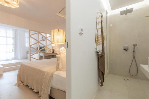 a white bedroom with a bed and a bathroom at Athina Studios and Suites Plaka in Plaka