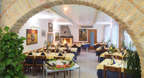 un ristorante con tavoli, sedie e un camino di Stella d'Oro a Marano Lagunare