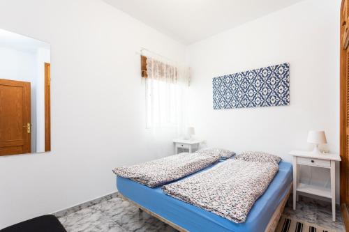 a small bedroom with a blue bed and a window at Casa Alcala in Alcalá