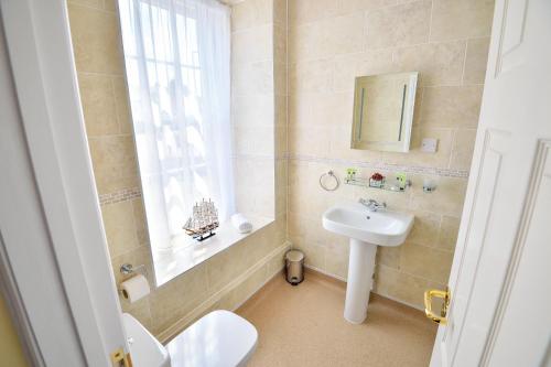 a bathroom with a sink and a toilet and a window at The George Hotel in Axminster