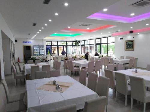 un comedor con mesas blancas y sillas blancas en Hotel MK, Plavi restoran, Loznica, en Loznica