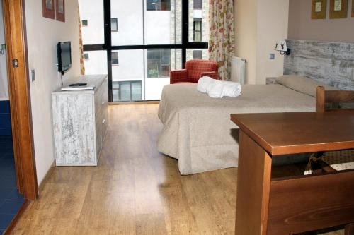 a bedroom with a bed and a tv and a table at Aparthotel La Vall Blanca in Vielha