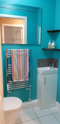 a blue bathroom with a toilet and a towel at Home2Home Meadow Close in East Kilbride