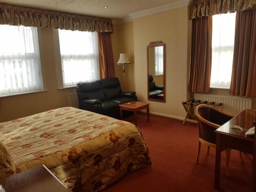 a hotel room with a bed and a chair and a mirror at Welbeck Hotel & Apartments IOM in Douglas