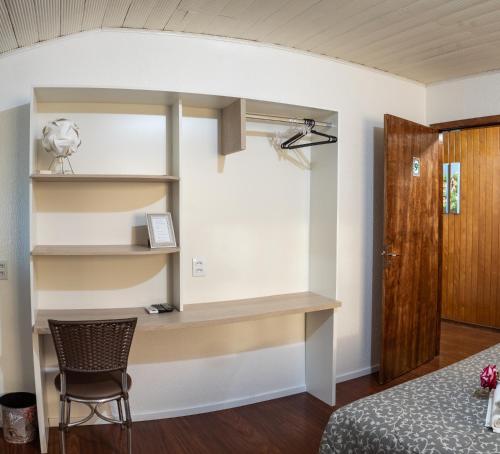 ベント・ゴンサルベスにあるPousada Don Mariniのベッド、デスク、椅子が備わる客室です。