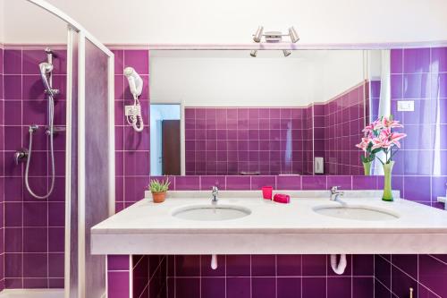 a purple bathroom with two sinks and a mirror at Lia Rooms 4 in La Spezia