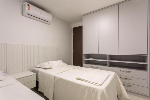 a white bedroom with two beds and a cabinet at Apartamento NOVO - Beira mar de Intermares in Cabedelo