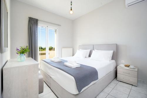 een witte slaapkamer met een groot bed en een raam bij Villa Cacasa in Khoumérion