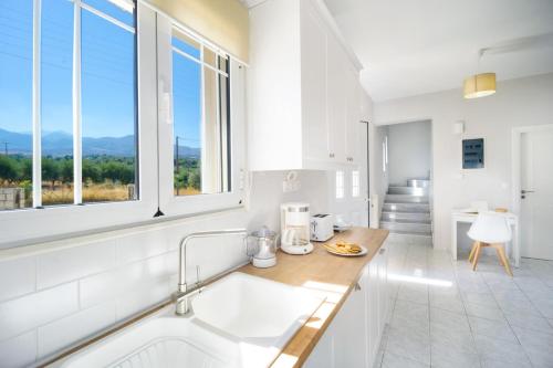 een witte keuken met een wastafel en een raam bij Villa Cacasa in Khoumérion