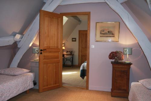 Zimmer im Dachgeschoss mit einer Tür, die zu einem Schlafzimmer führt in der Unterkunft La Main Ouverte in Fultot