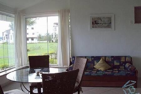 a living room with a table and a couch at Angra - Apto Pé na Areia - Bracuhy in Angra dos Reis