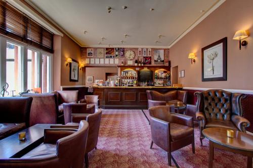 eine Bar in einem Restaurant mit Ledersesseln und Tischen in der Unterkunft The Ennerdale Country House Hotel ‘A Bespoke Hotel’ in Cleator