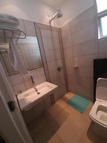 La salle de bains est pourvue d'un lavabo, d'un miroir et de toilettes. dans l'établissement D2W Residency Suites, à Nairobi