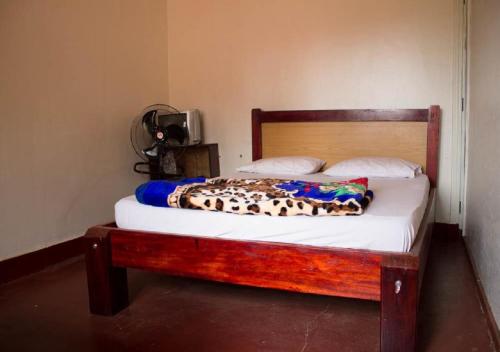 a bed in a room with a wooden bed frame at Okla GuestHouse in Kampala