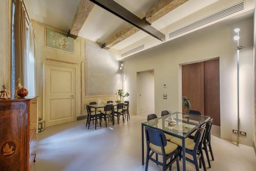 uma sala de jantar com uma mesa de vidro e cadeiras em Residenza d'Epoca Le Aquile em Siena
