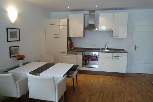 a kitchen with a dining room table and white cabinets at Ferienwohnung Meding am See in Schondorf am Ammersee