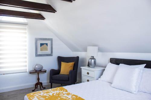 um quarto com uma cama e uma cadeira em Cavendish Heights Suites em Pembroke