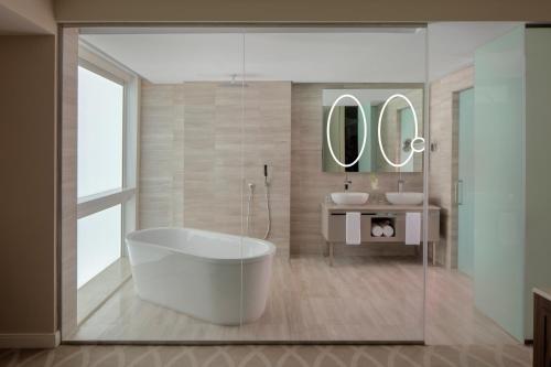 uma casa de banho com uma banheira grande e 2 lavatórios em Dusit Doha Hotel em Doha