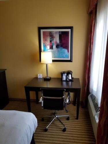 a desk in a hotel room with a lamp and a bed at La Quinta by Wyndham Atlanta Union City in Union City