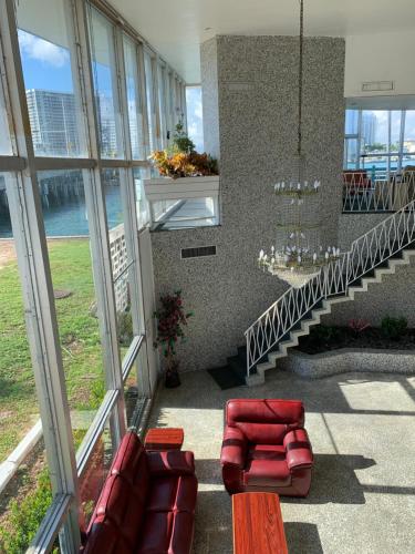 a lobby with red chairs and a staircase with windows at International Inn on the Bay in Miami Beach