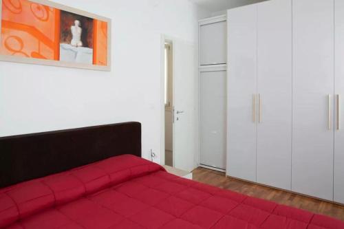 a red bed in a white room with a red blanket at Red House ai Mori in Venice