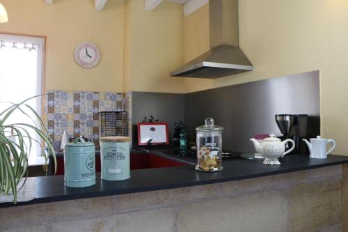 a kitchen with a counter top with jars and a clock at Chambres et Gîte PEYROUTAS " CAMILLE" Vignonet St Emilion in Vignonet