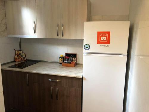 a kitchen with a white refrigerator and wooden cabinets at Вила Мечта in Starozagorski Bani