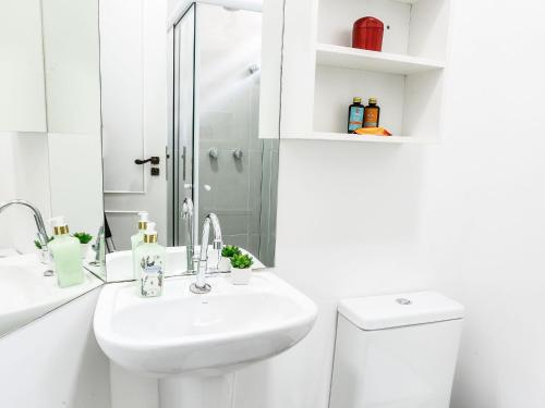 a white bathroom with a sink and a shower at Apartamento com quintal em Alto de Pinheiros in Sao Paulo