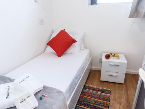 a small white bedroom with a red pillow on a bed at Apartamento com quintal em Alto de Pinheiros in Sao Paulo