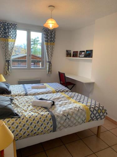 une chambre avec deux lits et un bureau et une fenêtre dans l'établissement SERRE CHEVALIER 1200, à Briançon