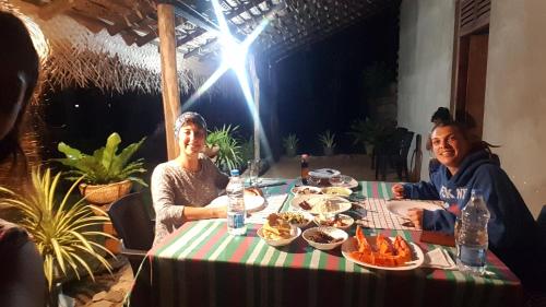 two women sitting at a table with food at lake paradise cabana in Tissamaharama