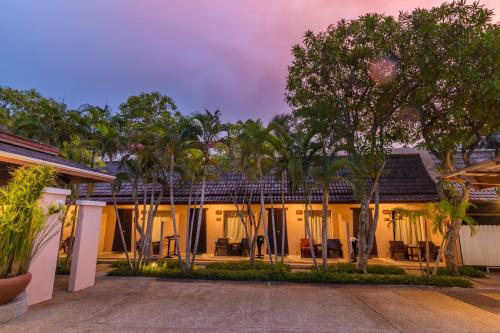 an exterior view of a house with trees at Phuket Kata Resotel in Kata Beach