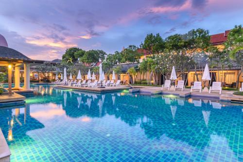 a pool at a resort with chairs and umbrellas at Phuket Kata Resotel in Kata Beach