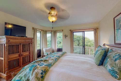 a bedroom with a bed with a tv and windows at Hanalei Bay Villas #33 in Princeville