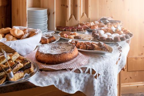 a table filled with different types of bread and pastries at Hotel Garni Soreie in Pozza di Fassa