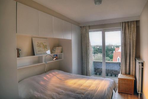 ein Schlafzimmer mit einem Bett und einem großen Fenster in der Unterkunft Zoutezoute in Knokke-Heist