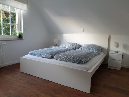 ein weißes Bett mit zwei Kissen auf einem Zimmer in der Unterkunft Ferienwohnung Marlena in Hage