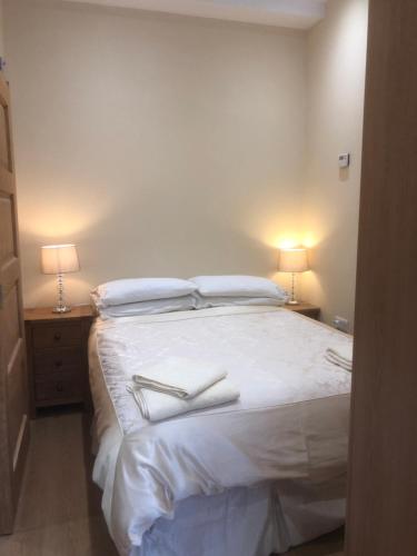 a bedroom with a large white bed with two lamps at Courtyard Studio in Armagh