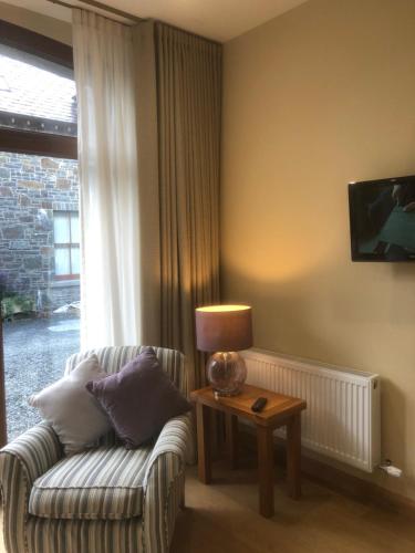 a living room with a couch and a table with a lamp at Courtyard Studio in Armagh