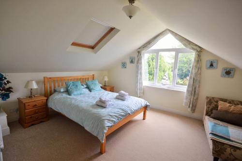 a bedroom with a bed with blue pillows and a window at Woodside Cottage in Godshill