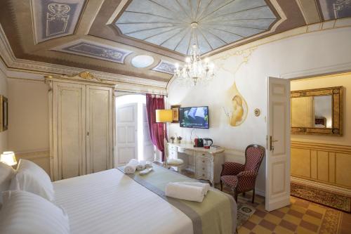 a bedroom with a bed with a desk and a chandelier at Les Suite Royales in Sassari