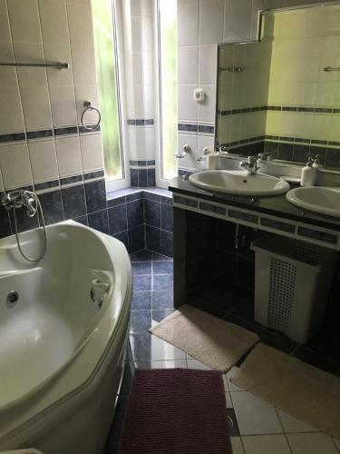 a bathroom with two sinks and a tub and a mirror at Megtart-lak Villa in Balatonszárszó