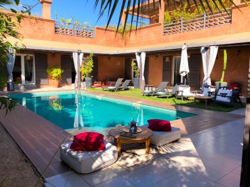 ein Pool mit Stühlen und einem Tisch neben einem Haus in der Unterkunft Palais Akki in Marrakesch