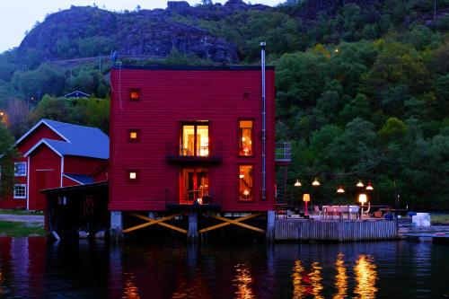 a red house on a dock in the water at Logbua - House on the Sea in Åna-Sira